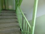 Klatka schodowa z metalowymi poręczami w kolorze jasnozielonym, na wprost schody