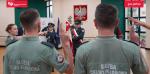 przysięga, funkcjonariusze podnoszą symboliczne dłonie, w tel poczet sztandarowy izby i godło Polski