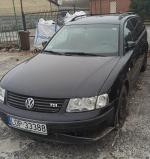 Czarny Volkswagen Passat kombi, uszkodzony zderzak, ogumienie w złym stanie, brak kołpaków, szyby bez widocznych uszkodzeń