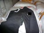 Dresowe spodnie męskie koloru czarnego leżą na pakunkach z zatrzymaną odzieżą.
